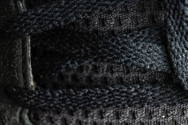 Siyah ayakkabı bağcıklarının kapalı ortamdaki kumaş dokusuna yakın plan çizimi.