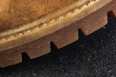 Ayakkabı tabanının yakın plan ayrıntıları koyu bir arkaplana karşı doku ve ayak izlerini ortaya çıkarıyor