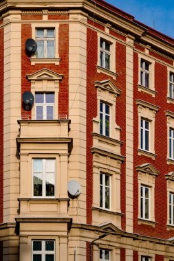 Açık mavi gökyüzü altında kentsel çanak antenli tuğla apartman