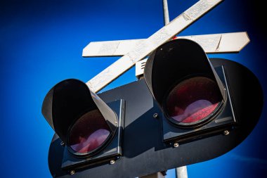 Demiryolu kavşağındaki trafik işaretleri güneşli bir günde tehlikeyi işaret ediyor.