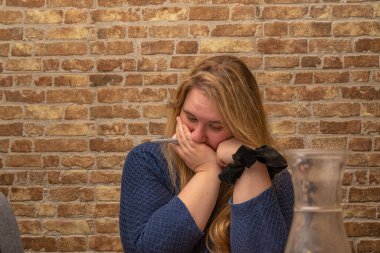 Perplexed Woman focused on completing 1040 US income tax form in a cozy indoor setting clipart