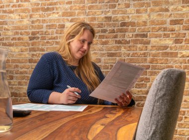 Perplexed Woman focused on completing 1040 US income tax form in a cozy indoor setting clipart