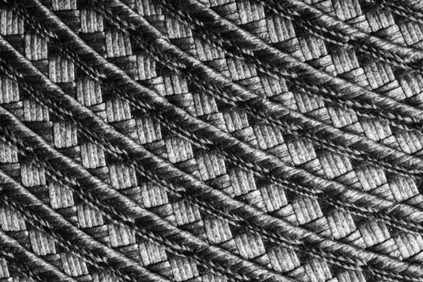 Bu resim, iç içe geçmiş ipliklerin oluşturduğu desenleri ve dokuları vurgulayan dokuma malzemesinin detaylı bir yakın çekimini içeriyor..