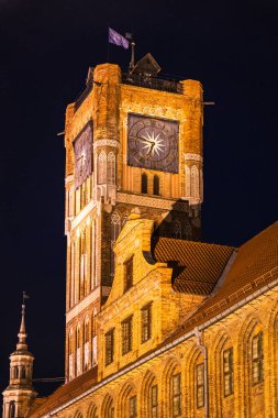 Gece gökyüzüne karşı aydınlatılan Torun 'daki Eski Kasaba Kulesi, ortaçağ mimarisinin bir sembolü, büyüleyici ziyaretçiler olarak duruyor..