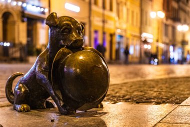 Profesör Filutek 'in şapkasını tutan çizgi roman köpeği Filus' un geceleri sessiz bir caddeyi aydınlattığı hoş bir heykel..
