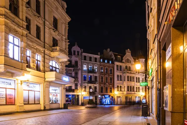 Dükkanlar, eski Torun kasabasını kaplayan gece gibi ışıldıyor. Zegar saat kulesi, sakin sokakların ortasında gururla duruyor..