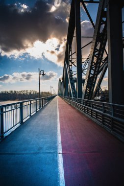 Köprü boyunca uzanan uzun bir yaya geçidi ışıldayan sokak lambaları ve büyüleyici bir gece gökyüzü ile çevrili..