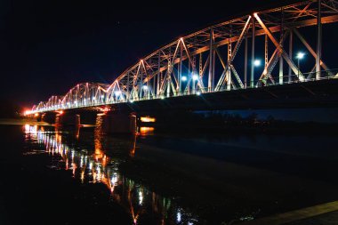 Sakin sularda güzel aydınlatılmış bir köprünün çarpıcı yansımasına hayret ediyorum. Geceleri sakin bir nehir kenarı sergiliyor..