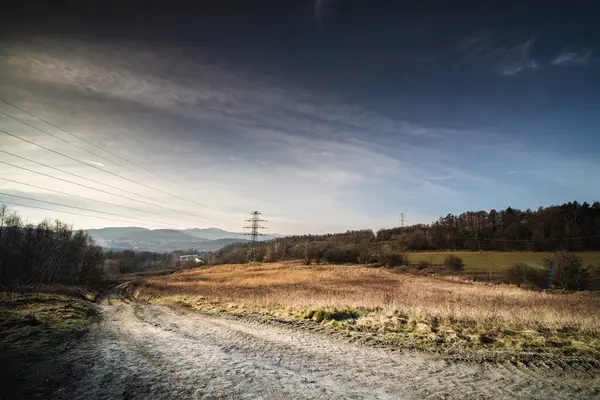 Uçsuz bucaksız, evcilleştirilmemiş topraklar, elektrik hatlarının dramatik bir gökyüzünün altında ufku izlediği yuvarlanan tepelere uzanıyor..