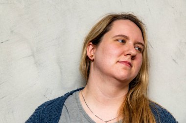 Tarafsız bir zemine hafifçe gülümseyen, samimi bir ortamda sıcaklık ve mutluluk saçan uzun saçlı bir anne..