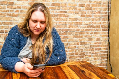 Sıcak ve dokulu bir ortamda, güzel bir anne, huzurlu bir yalnızlık anına dalmış akıllı telefonuna odaklanır..