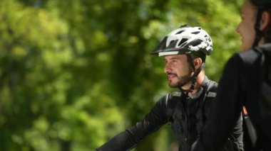 Bisikletçi kasklı genç bir Orta Doğulu kadın ortağını işaret ediyor..