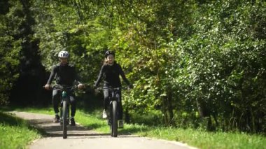 Güneşli bir yaz gününde bisiklet süren genç bir adam ve kadın tam teçhizatlı..