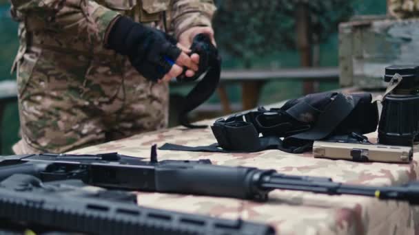 Солдат Снимает Перчатки Столе Видны Ружья — стоковое видео