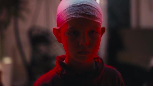 Biały Chłopiec Bandażem Głowie Patrzący Przed Siebie Gdy Oświetlają Światła — Wideo stockowe