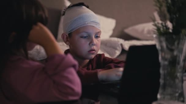 Niebieskooki Białas Bandażem Głowie Patrzący Ekran Obok Siostry Dziecko Wypełnia — Wideo stockowe