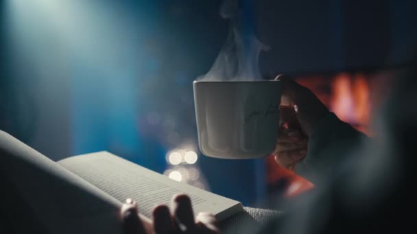 Женщина Наслаждается Уютным Вечером Чашкой Чая Книгой Камина Теплая Атмосфера — стоковое видео