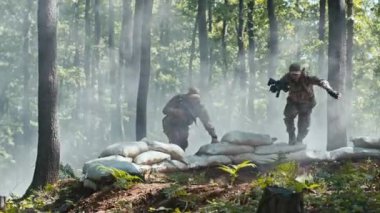 Taktik tatbikat sırasında iki asker bir orman kum torbası sığınağına atladı. Profesyonel takım çalışması, açık hava eğitimi ve duman efektleri askeri tatbikatlarına yoğunluk katıyor..