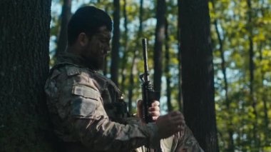 Ormanda yorgun bir asker şarjörünü kontrol ediyor ve cephanesinin azaldığını fark ediyor..