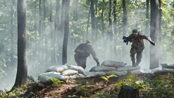 戦術演習中に2人の兵士が森林サンドバッカーに飛び込んだ 専門のチームワーク 屋外訓練および煙の効果は軍の訓練に強さを加えます — ストック動画