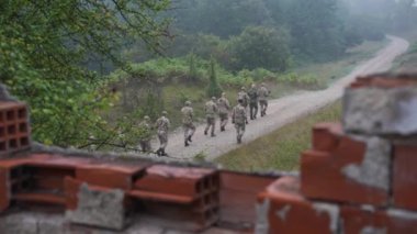 Askeri birlik komuta altındaki toprak bir yola giriyor. Birlikler disiplin ve birlik sergiliyor.