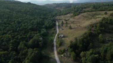 Bosna 'da yolun yanındaki harap evlerin havadan görünüşü, çatışma ve savaş kalıntıları. Manzara yıkımın izlerini taşıyor, yıkılmış binalar, enkaz ve ıssızlıkla..