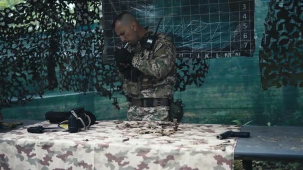 一名身穿制服的军事指挥官站在一个自然基地时吸烟 — 图库视频影像