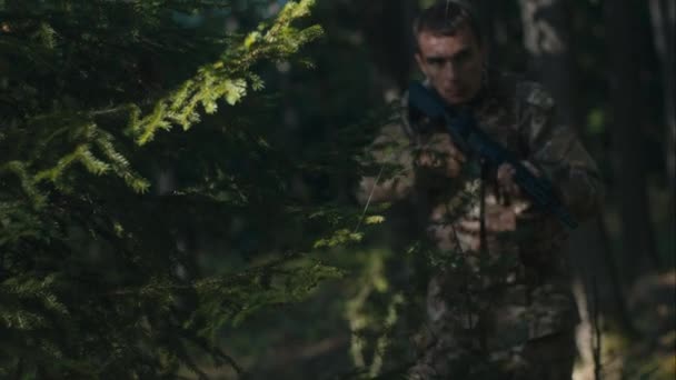 彼のライフルを保持する熟練した兵士は 森で位置を撃つ準備ができています — ストック動画