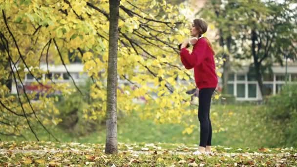 フィット若い女性は屋外に伸びるために彼女のジョギングを一時停止し スマートフォンをチェックし ジョギングを続けます 秋の健康的なルーチン中にフィットネス 自然を取り入れる — ストック動画