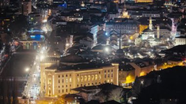 Geceleri Sarajevos Old Town 'da. Aydınlatılmış simgeler ve geçen arabalar zengin bir şehir manzarası yaratır. Bu tarihi Bosna şehrinin güzelliğini keşfedin.