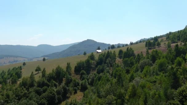 自然に囲まれた山のクリアリングに 遠隔地の孤立したコテージの空中ビューに近づく 晴れた夏の日には 孤独と緑の山腹を特徴とする風景 — ストック動画