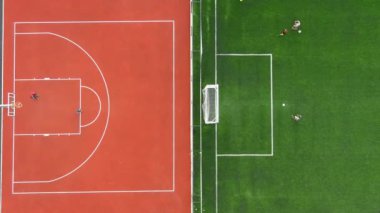 Çocuklar bitişik tarlalarda basketbol ve futbol oynarlar. Havadan yukarıdan aşağıya bakış, aktif çocukluğun özünü yakalar, eğlence, eğlence ve takım sporları açık hava ortamında bir araya gelir..