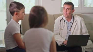 Sıcak bir odada, danışma sırasında çocuklarla profesyonel bir konuşma yapan bir doktor. Sıcak bir ortamda sağlık, aile iletişimi ve pediatrik bakım kavramı.