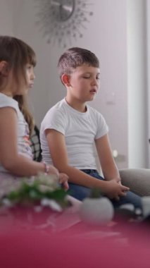 Dikey ekran: genç kız evde gergin bir oğlanın yanında otururken konuşuyor, ikisi de endişe ve huzursuzluk belirtileri gösteriyor, sanki ciddi bir konuşmada gibi. Çocukluk duyguları kavramı.