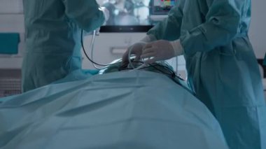Steril önlüklü cerrahlar modern bir ameliyathanede endoskopik ekipman hazırlıyorlar. Hassasiyet, ileri tıbbi teknoloji ve sağlık hizmetleri kavramı.