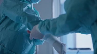 Cerrahi önlüklü ve eldivenli tıp uzmanlarının steril bir ortamda takım çalışmasına odaklanarak bir prosedüre hazırlandığı yakın plan. Sağlık hazırlığı ve tıbbi ekip çalışması kavramı.