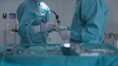 Steril bir ameliyathanede özel aletlerle minimal invaziv prosedür uygulayan cerrahların yakın çekimi. Modern cerrahi, hassasiyet ve sağlık hizmetlerinde takım çalışması kavramı.
