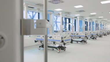 Modern hastane koğuşunda sıra sıra gelişmiş tıbbi yataklar, parlak iç mekan ve temiz tasarım var. Sağlık altyapısı, tıbbi teknoloji ve profesyonel tesisler kavramı.