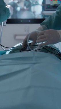 Dikey Ekran: Steril önlüklü cerrahlar modern bir ameliyathanede endoskopik ekipman hazırlıyorlar. Hassasiyet, ileri tıbbi teknoloji ve sağlık hizmetleri kavramı.