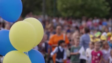 Ön planda mavi ve sarı balonlar ve okula dönüş etkinliğinde çocukların ve ebeveynlerin bulanık bir geçmişi var. Eğitim, toplum ve festival toplantıları kavramı.