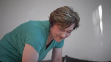 Parlak ve minimalist bir ortamda ev işi yaparken gülümseyen orta yaşlı bir kadının yakın çekimi. Pozitiflik, ev yapımı ve aile sorumluluğu kavramı