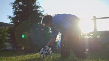 Kıdemli kadın, güneşli bir günde küçük köpeğiyle güzel vakit geçirir, hayvanı sevmek için eğilir. Arkadaşlık, açık hava eğlencesi ve hayvan bakımı kavramı..