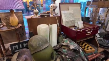 Konforlu bir antikacıda sergilenen eski askeri eserler, eski haritalar ve eski mobilya koleksiyonu. Tarih kavramı, nostalji ve koleksiyoncular ve meraklılar için zamansız tasarım.