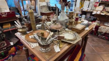 Antika mağazasının içi gümüş takımlar, pirinç süsler ve eski eserler gibi antika eşyalarla dolu. Tarihi veya sanatsal objelerin toplanması ve sergilenmesi kavramı.