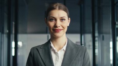 Kendine güvenen bir iş kadınının resmi bir takım elbise giymiş kurumsal bir ofis ortamında içten bir şekilde gülümsemesi. Profesyonellik, liderlik ve olumlu çalışma ortamı kavramı.
