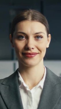 Kendine güvenen bir iş kadınının resmi bir takım elbise giymiş kurumsal ofis ortamında samimi bir şekilde gülümsemesi. Profesyonellik, liderlik ve olumlu çalışma ortamı kavramı.