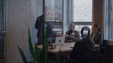 Genç bir kadın, cam duvarlı bir konferans odasında modern bir iş toplantısında katılımcılara kağıtları dağıtıyor. Takım çalışması, liderlik ve profesyonel işbirliği kavramı.