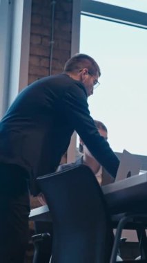 Dikey Ekran: Bir grup profesyonel, geniş pencereleri ve doğal ışığı olan modern bir ofis ortamında işbirliği yapıyor. Takım çalışması kavramı, iş stratejisi, dinamik bir çalışma alanında kurumsal toplantılar.