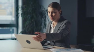 Stresli iş kadını laptopunu kapatıyor ve modern ofis ortamında çalışmalarını yansıtıyor. İş yeri kaygısı, karar yorgunluğu ve kurumsal tükenmişlik kavramı.