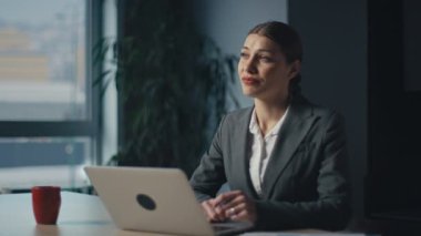 Modern bir ofiste dizüstü bilgisayar üzerinde çalışan profesyonel bir iş kadını heyecan, mutluluk ve odaklanma gösteriyor. Şirket işi, kariyer gelişimi ve profesyonel duygular kavramı.